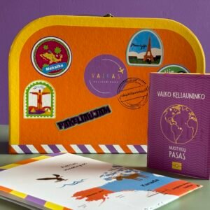 Bright orange suitcase covered in colorful travel stickers sits beside a purple notebook and printed maps on a desk against a purple wall.