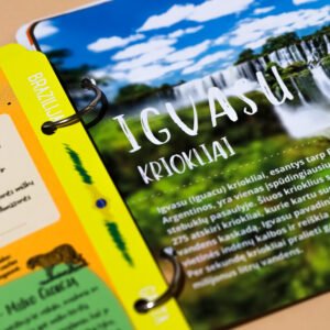 Close-up of a glossy travel brochure held in a bright yellow binder, showing a blue sky with white clouds and bold white text partially visible at the edge grip ring near the binder.