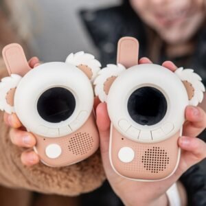 Two cartoon-like toy cameras held up for a photo, each with a large circular eye lens and fluffy ears, in pink and white.