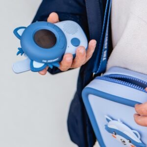 Child's hand holding a blue toy camera with a circular screen and buttons labeled The Zoo Family.